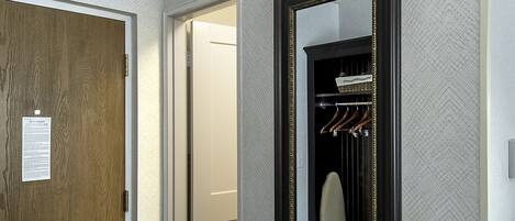 Un pasillo con una puerta de madera, un espejo y un perchero.