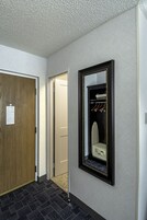A hallway with a wooden door, a mirror, and a coat rack.