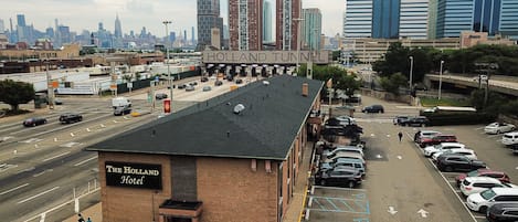 The Holland Hotel with a parking lot and a view of the Holland Tunnel and city skyline.