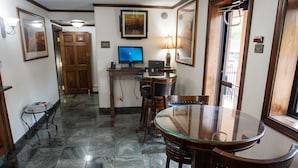 Un comedor con una mesa de vidrio, sillas de madera, una lámpara en el techo y un televisor sobre un mueble.