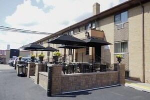 Un edificio con mesas al aire libre, un muro de ladrillo y un estacionamiento.