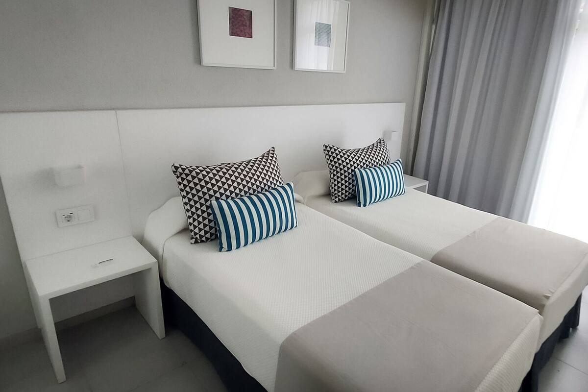 Una habitación de hotel con dos camas, una mesita de noche y una silla.