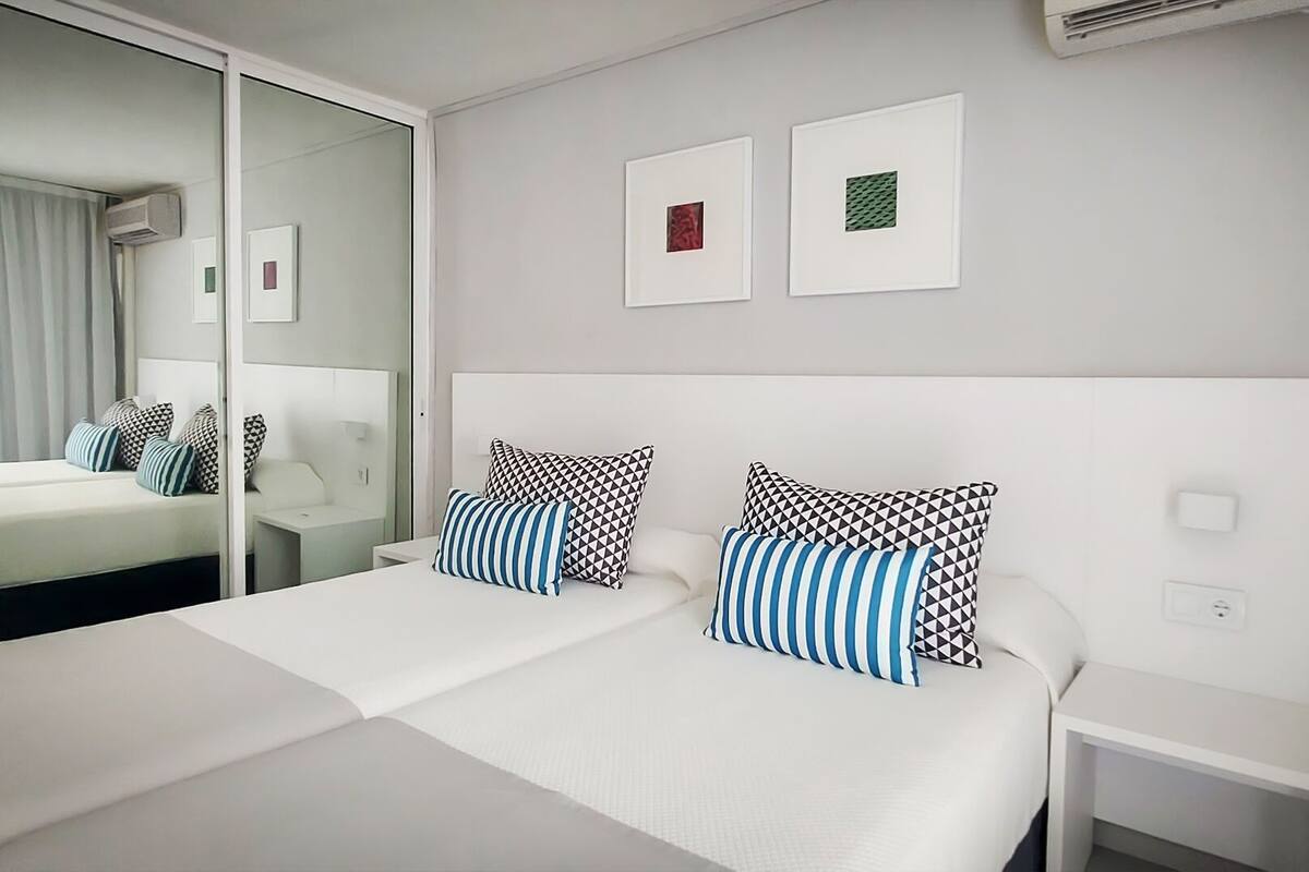 Habitaci ón de hotel con una cama grande, una mesita de noche, un espejo y dos cuadros en la pared.