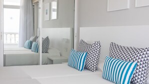 Quarto de hotel moderno com uma cama grande, mesa de cabeceira e espelho.