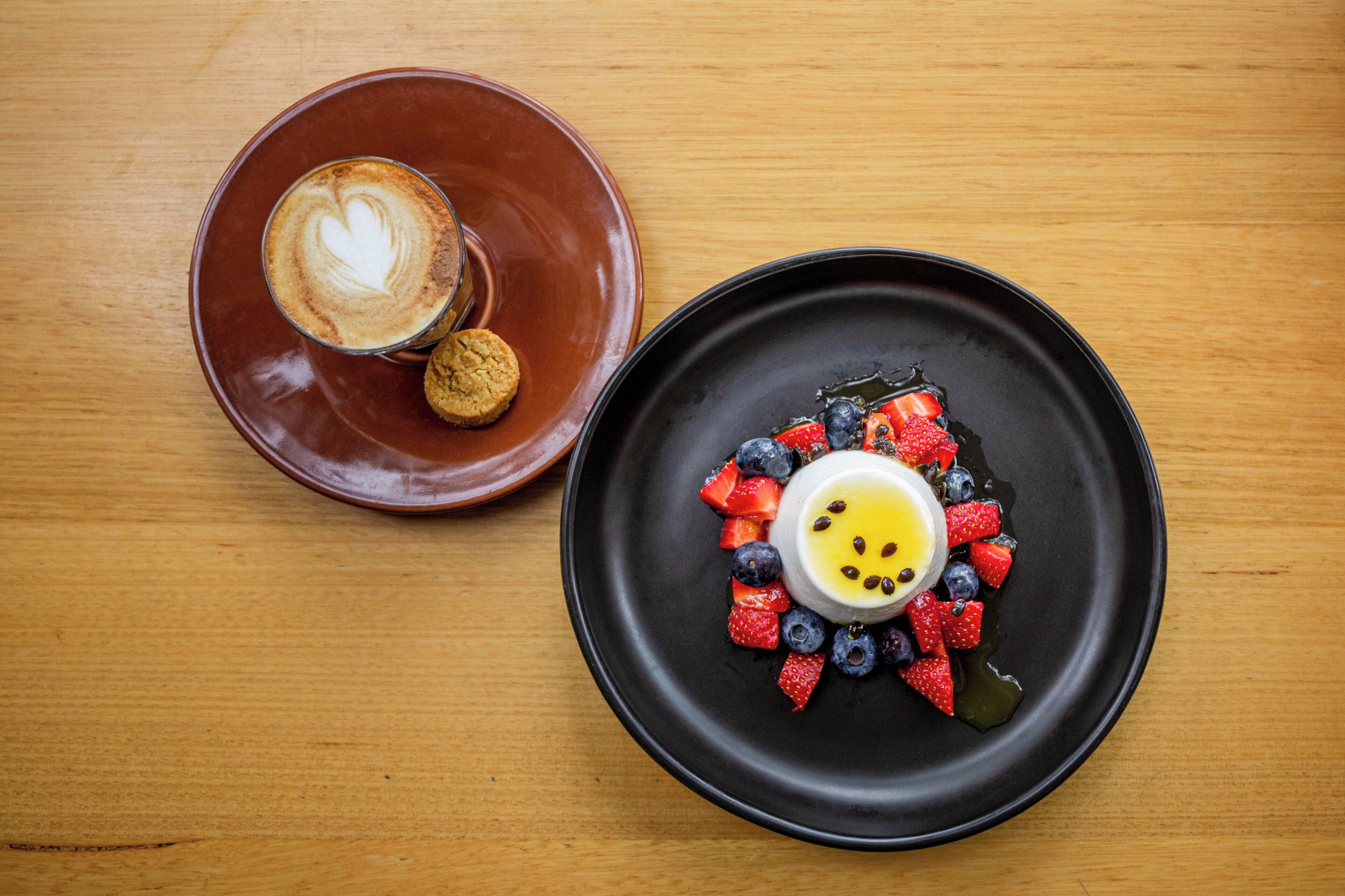 Un plato para postre con un diseño en forma de corazón sobre una taza de café en una mesa de madera.