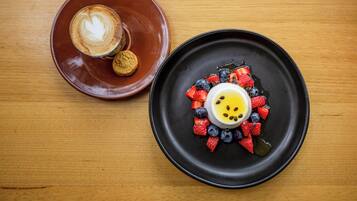 Un plato para postre con un diseño en forma de corazón sobre una taza de café en una mesa de madera.
