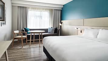 Habitación de hotel con una cama grande, un sofá, una mesita y una silla.
