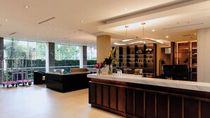 A modern hotel lobby with a reception desk, seating area, and a large window offering a view of greenery. - Crowne Plaza Sydney Macquarie Park by IHG (Macquarie Park)