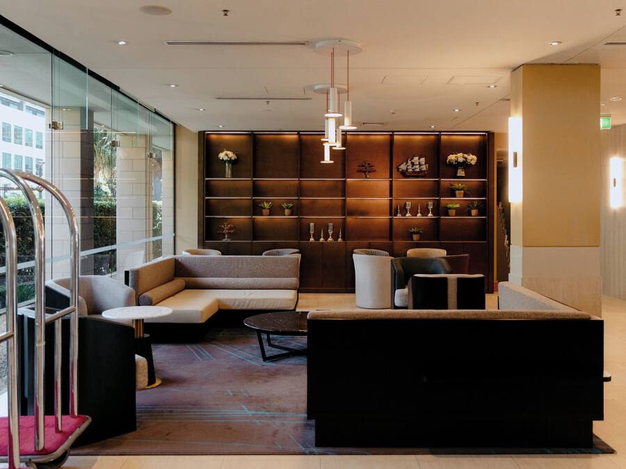 Un vestíbulo moderno con zona de estar, un mostrador de recepción y una pared con estantes que exhiben objetos decorativos.
