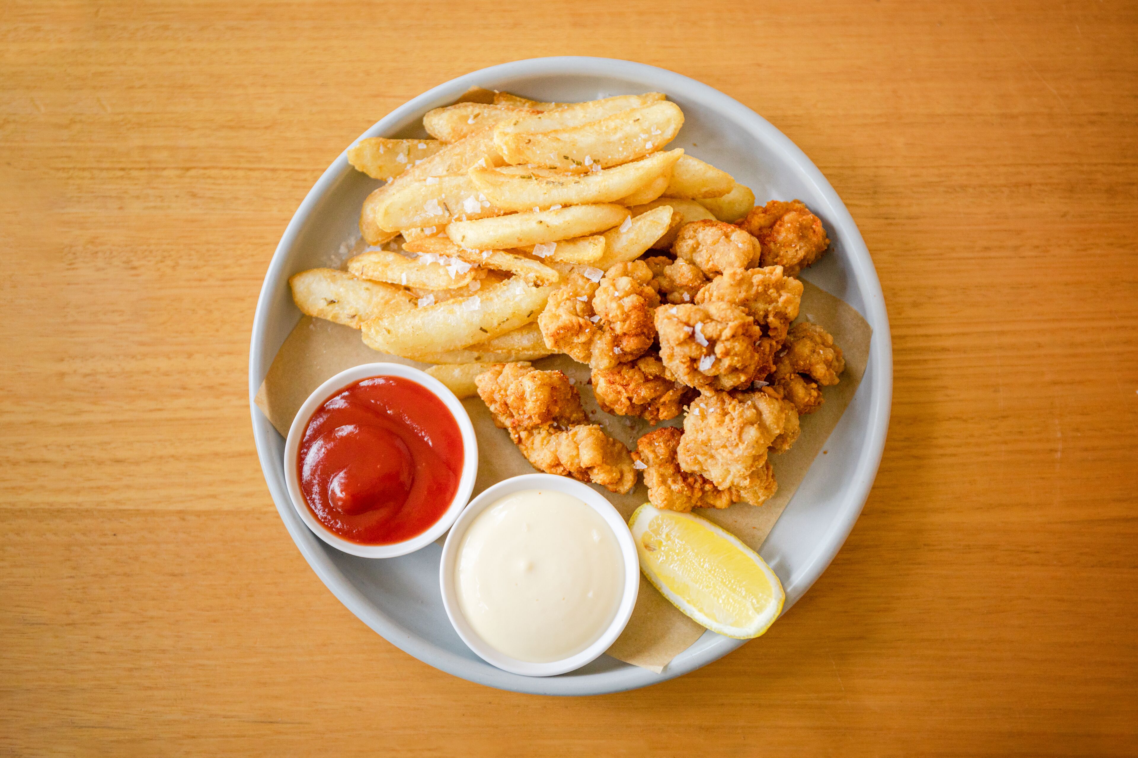 En tallrik med kycklingnuggets, pommes frites, ketchup och majonnäs.