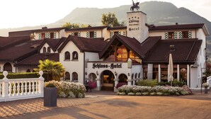 A hotel with a traditional European architectural style, featuring multiple arches and a prominent entrance. - Swiss-Chalet Merlischachen - Romantik Schloss-Hotel am See (Kuessnacht)