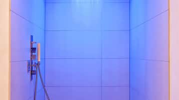 Une salle de douche moderne avec une pomme de douche illuminée en bleu et un panneau de commande fixé au mur.