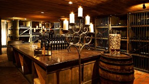 A bar area with a wooden bar, multiple wine bottles on shelves, and a large barrel. - Swiss-Chalet Merlischachen - Romantik Schloss-Hotel am See (Kuessnacht)