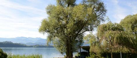Un área de estar al aire libre frente al lago, con sillones de descanso y un porche cubierto.