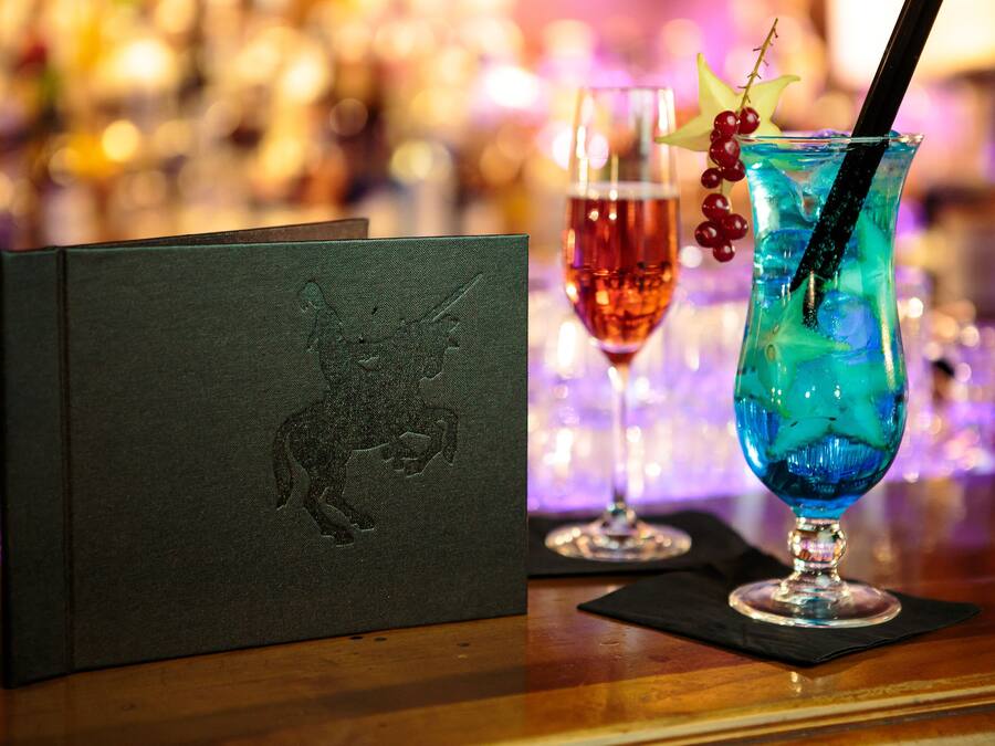 Un bar con una copa de cóctel, una carta y una copa de vino tinto.