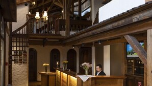 A rustic lobby with wooden beams, a reception desk, and a staircase leading to an upper level. - Swiss-Chalet Merlischachen - Romantik Schloss-Hotel am See (Kuessnacht)