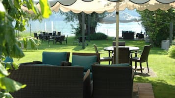 Une terrasse extérieure aménagée avec des meubles en osier, une table ronde et une vue sur le lac.