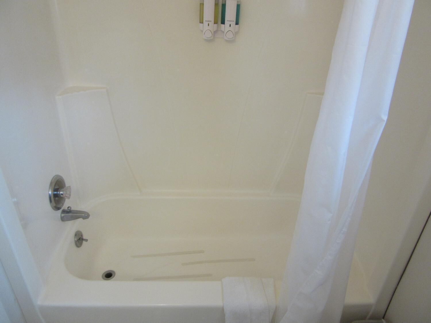 Een badkamer met een bad, toilet en douchegordijn.