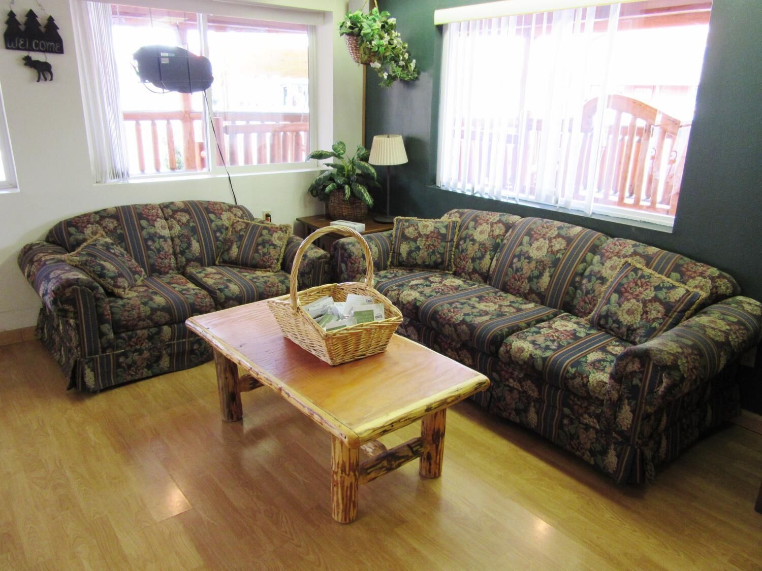 A living room with two patterned sofas, a wooden coffee table with a basket, and a lamp.