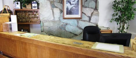 A reception desk with a stone wall backdrop, a framed picture, and a computer monitor.