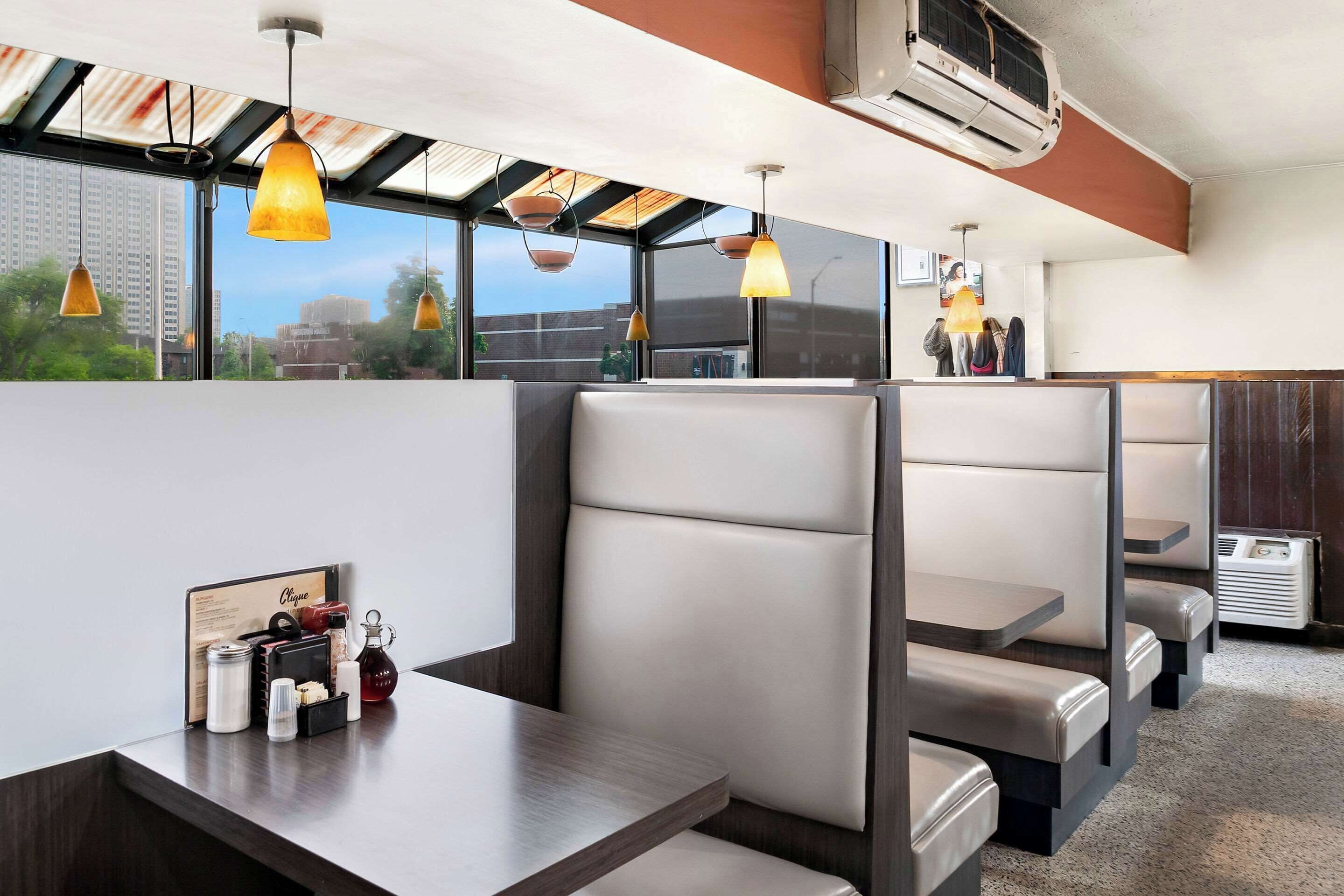 A modern restaurant with high tables and booths, large windows, and pendant lighting.