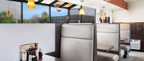 A modern restaurant with high tables and booths, large windows, and pendant lighting.
