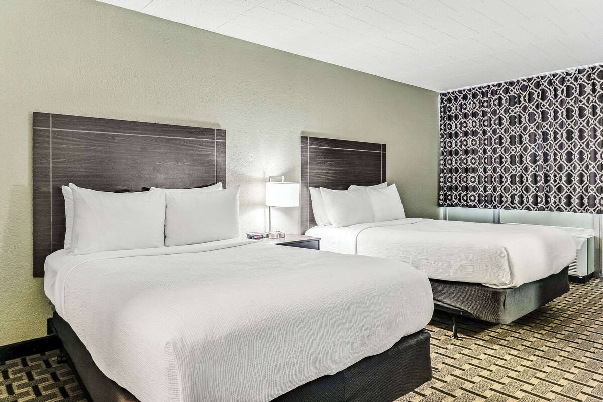 A hotel room with two beds, a patterned wall, and a patterned floor.