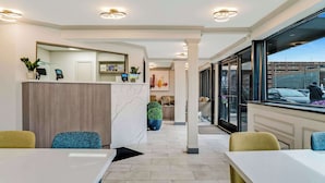 A modern hotel lobby with a reception desk, seating area, and large windows offering views of the city.
