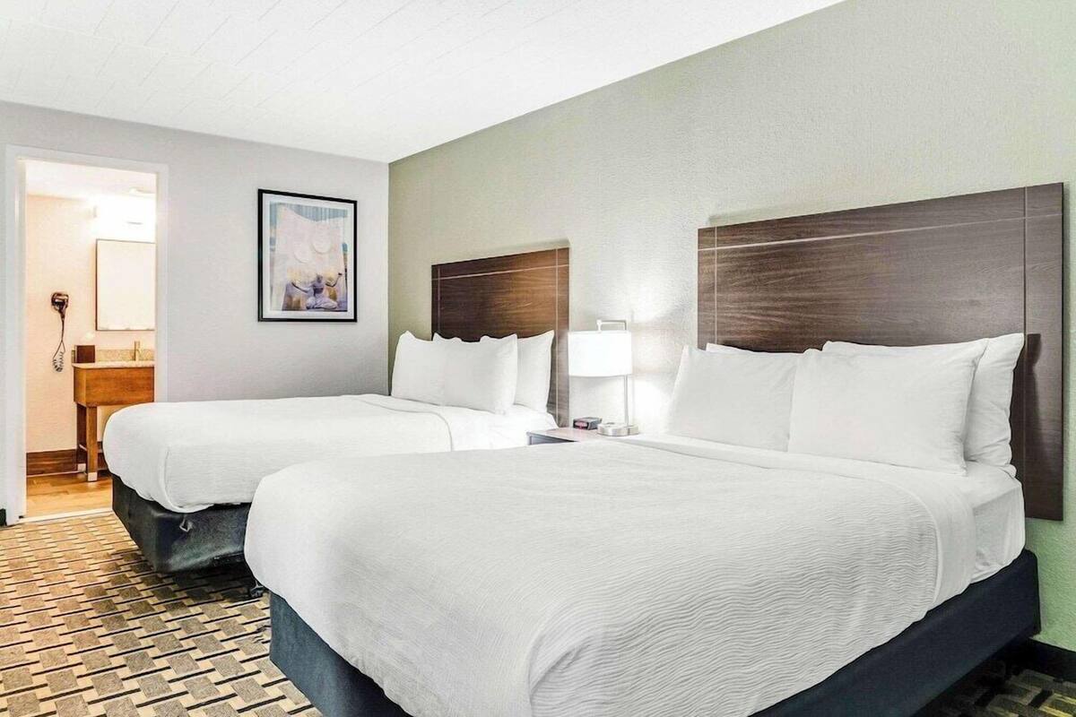 A hotel room with two beds, a wooden headboard, a framed picture on the wall, and a patterned floor.