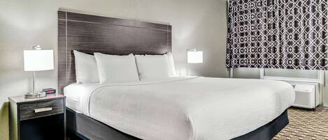 A hotel room with a large bed, two bedside tables with lamps, a patterned wall, and a patterned floor.
