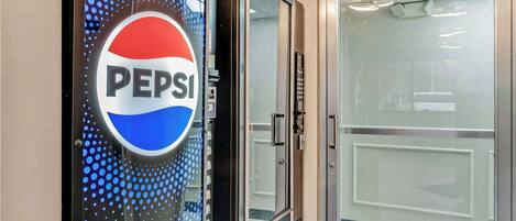 A door with a Pepsi logo and a glass door leading to a room.