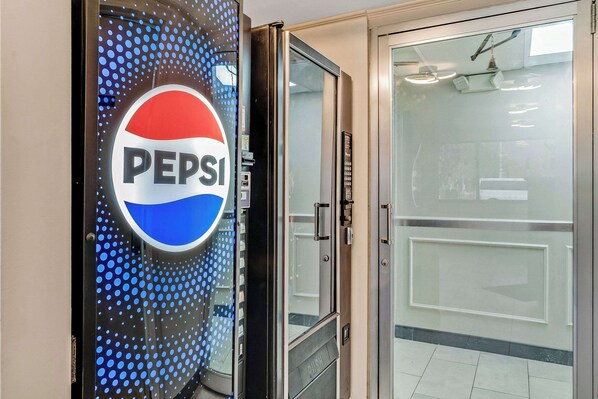 A door with a Pepsi logo and a glass door leading to a room.