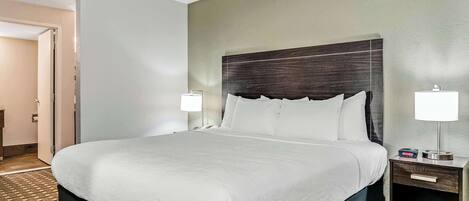 Una habitación de hotel con una cama grande, dos mesitas de noche con lámparas y una alfombra estampada.