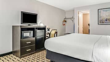 Una habitación de hotel con cama, televisión, minibar, escritorio y silla.