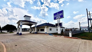A hotel entrance with a prominent sign reading 'Luxury Inn' and a sign stating 'The Lap of Luxury.' - Luxury Inn & Suites Liberty (Liberty)