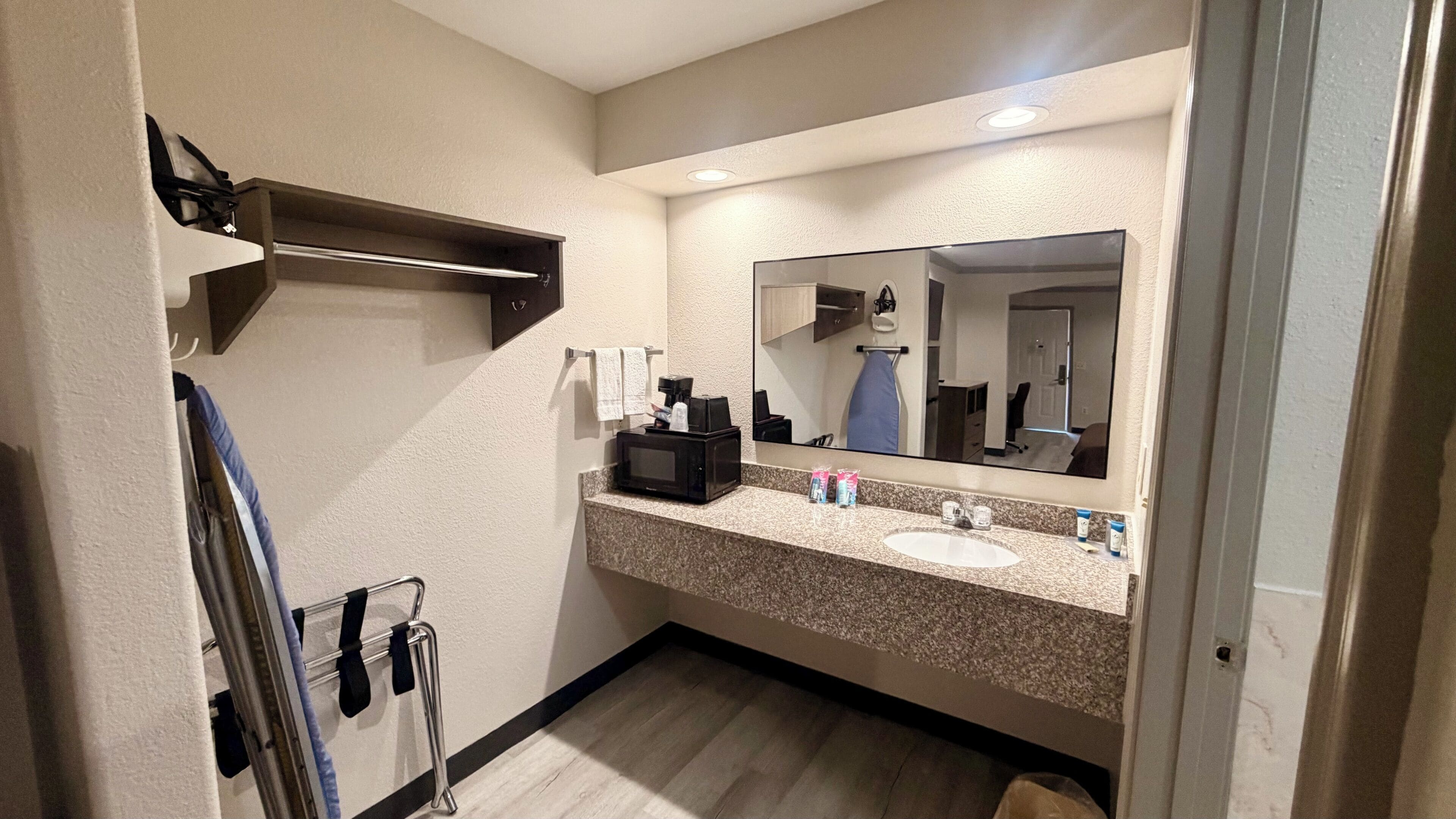 Un baño con lavamanos, espejo y perchero para toallas.