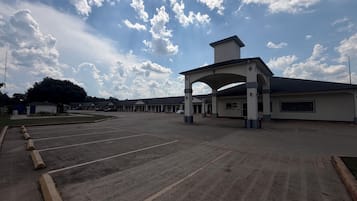 A motel with a large parking lot, a covered entrance, and a row of single-story buildings.