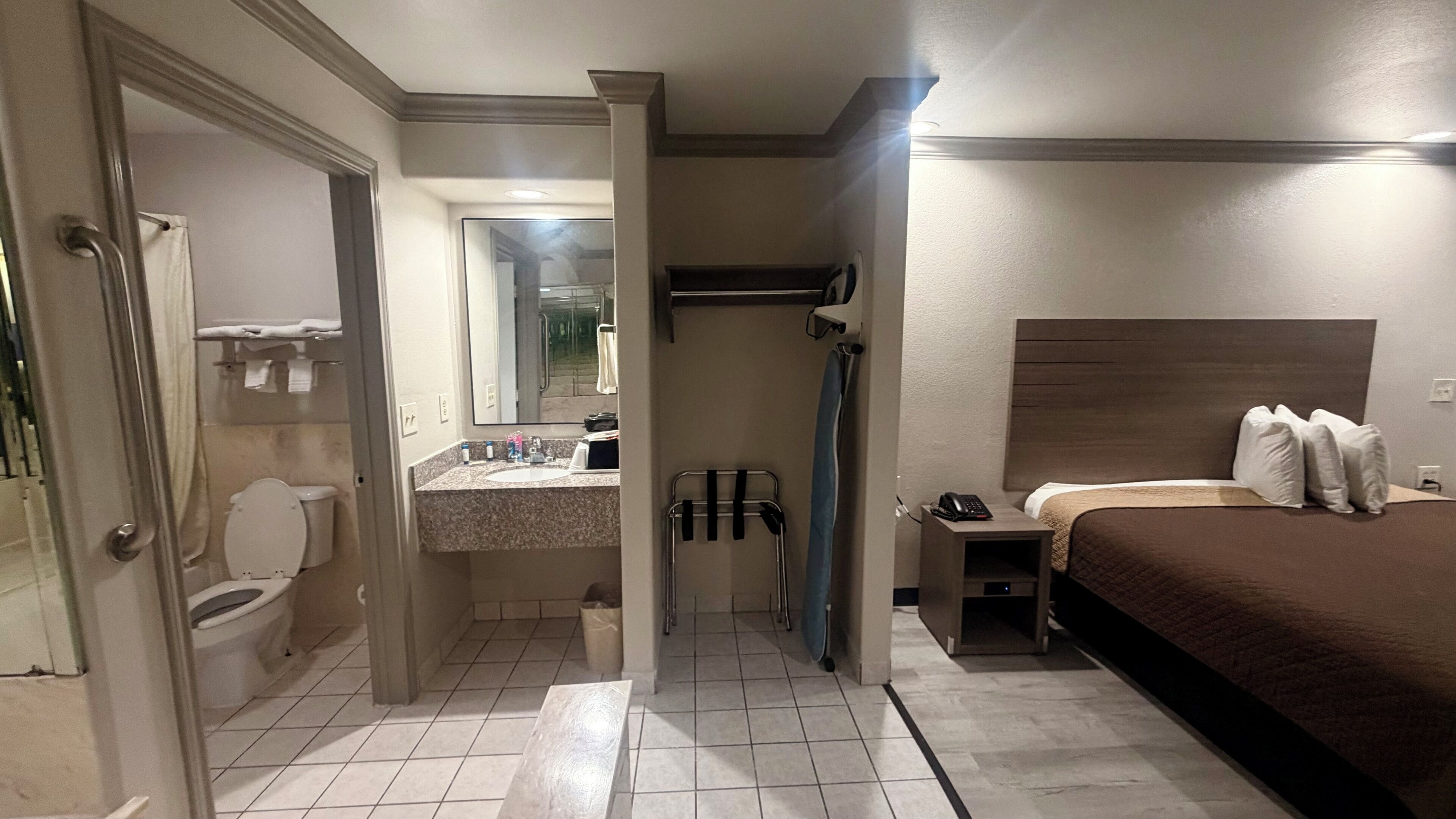A hotel room with a bathroom, a bed, and a shower area.
