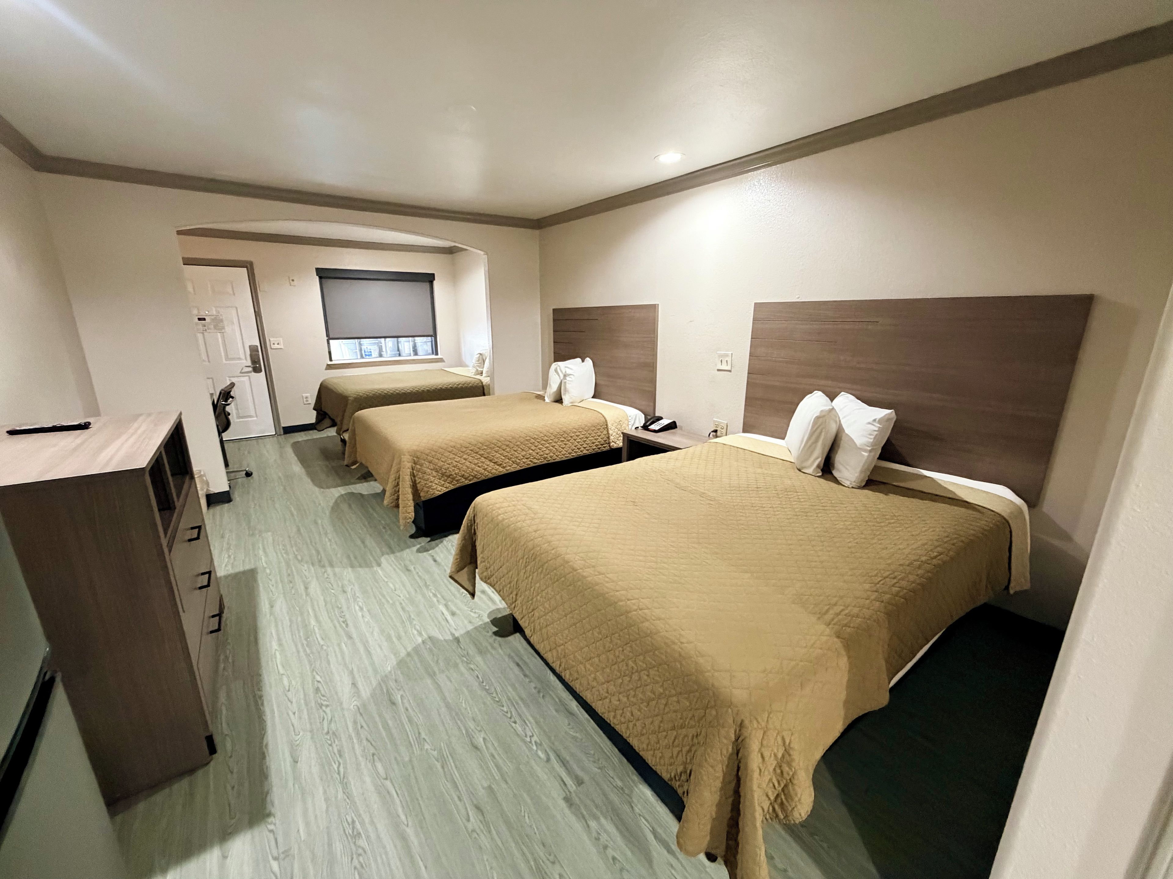A hotel room with two beds, a desk, and a wardrobe.