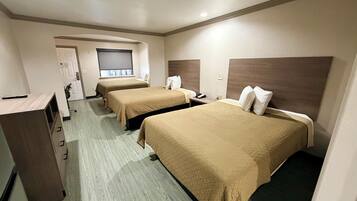 A hotel room with two beds, a desk, and a wardrobe.
