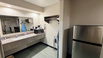 A hotel bathroom with a sink, mirror, and a Vissani refrigerator.