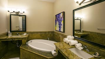 A bathroom with a bathtub, two sinks, and a large mirror.