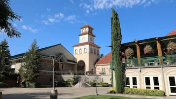 A building with a clock tower, a balcony with potted plants, and a well-maintained courtyard.