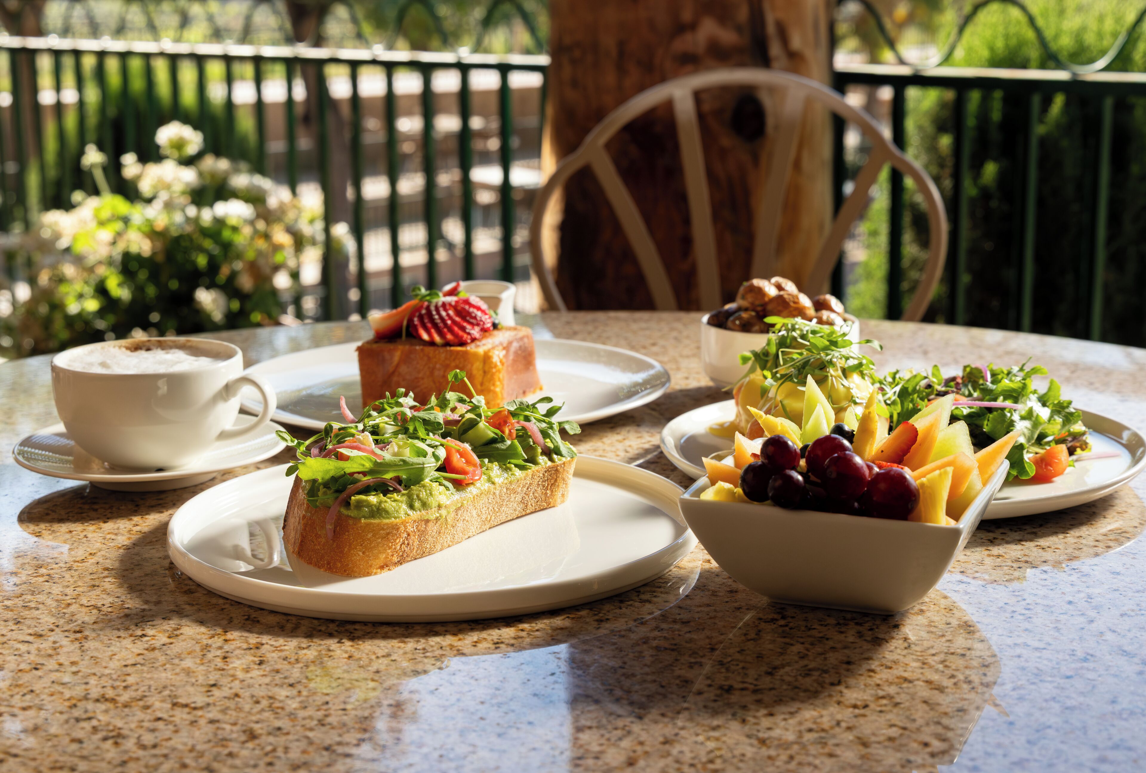 A table with plates of food, a cup, and a chair.