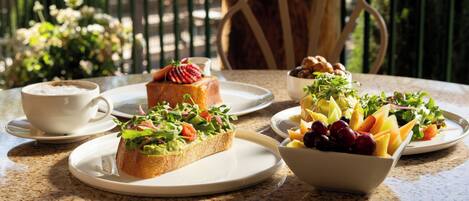 A table with plates of food, a cup, and a chair.