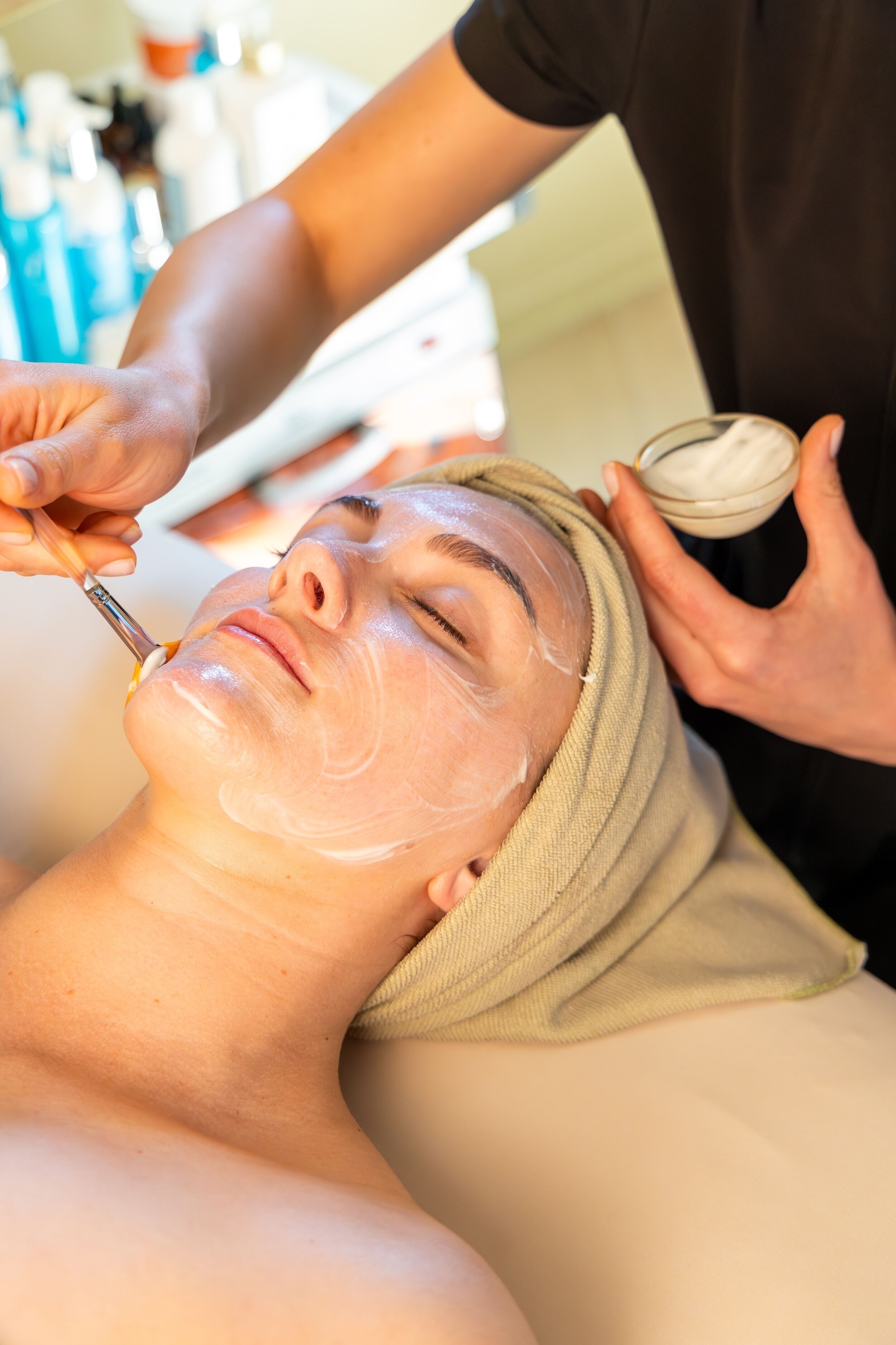 A person receiving a facial treatment with a towel wrapped around their head.