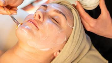 A person receiving a facial treatment with a towel wrapped around their head.