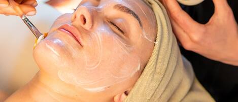 A person receiving a facial treatment with a towel wrapped around their head.