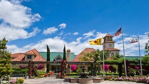 A building with a red-tiled roof, a bell tower, and multiple flags. - South Coast Winery Resort and Spa (Temecula)