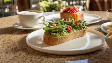 Una mesa con un sándwich, una taza y un postre sobre platos.